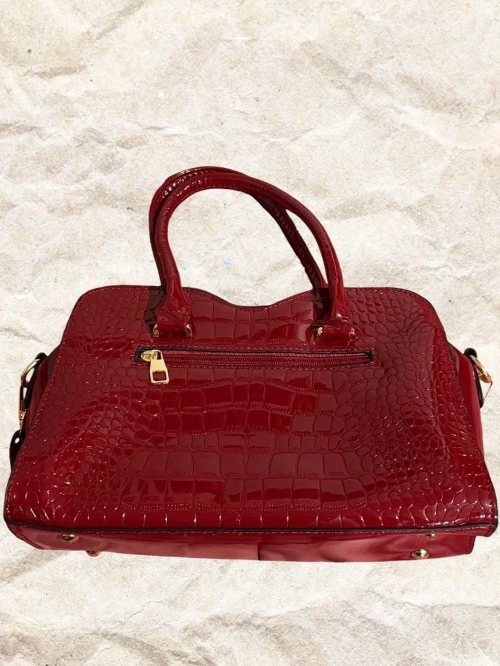 Red crocodile textured bow bag with gold hardware with removable strap